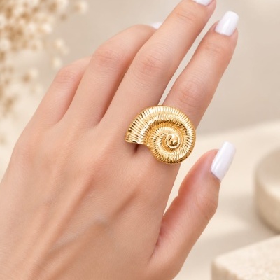 Anel dourado em espiral na mão com unhas brancas