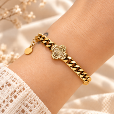 Pulseira dourada com pendente floriv em pulso feminino