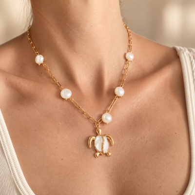 Colar dourado com pérolas e pendente de tartaruga no pescoço de mulher