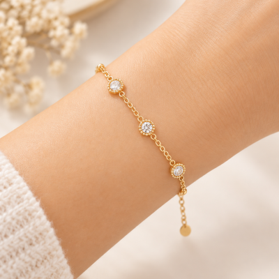 Pulseira dourada fina com pedras redondas num pulso