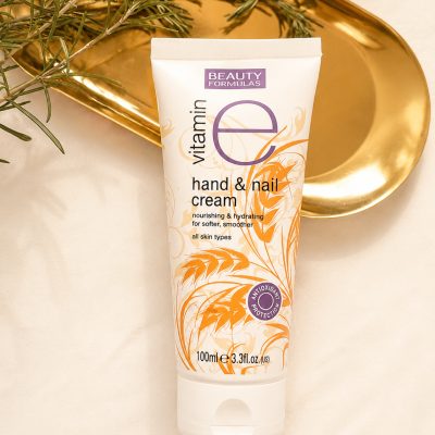 Creme para mãos e unhas Vitamin E da Beauty Formulas em tubo branco com detalhes laranja sobre bandeja dourada