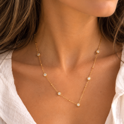Colar dourado com pedras brilhantes em modelo com camisa branca