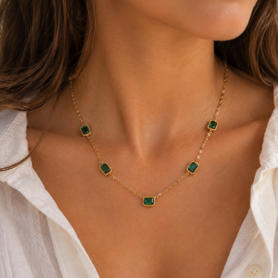 Colar dourado com pedras verdes em modelo com camisa branca