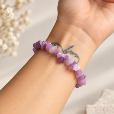 Pulseira de contas roxas no pulso de uma pessoa com tatuagem