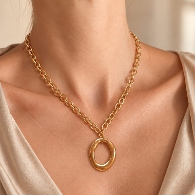 Colar dourado com corrente de elos grossos e pendente oval irregular no pescoço