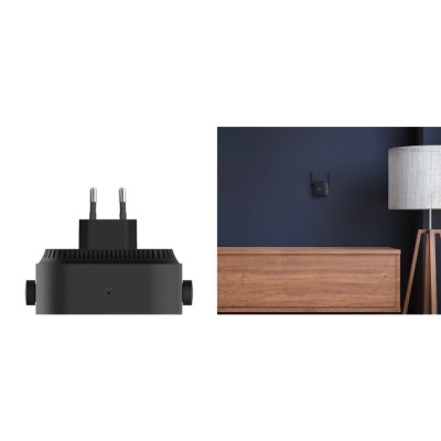 Adaptador de tomada preto plugado numa parede com móvel de madeira e luminária ao lado