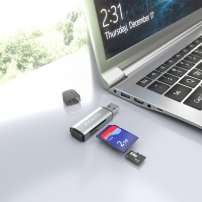 Computador portátil prateado com leitor USB AiSENS, cartão SD azul 2 GB e cartão microSD preto 2 GB numa superfície branca