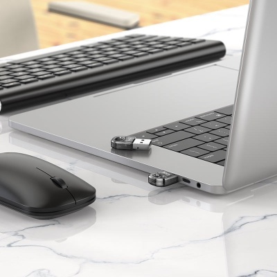 Computador portátil prateado com pen drives e rato preto em superfície de mármore