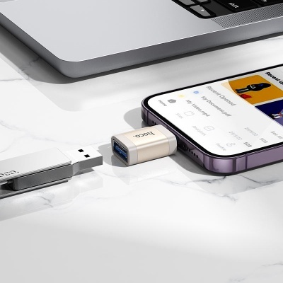 Dispositivos USB conectados a smartphone próximo de computador portátil sobre mesa de mármore branco.