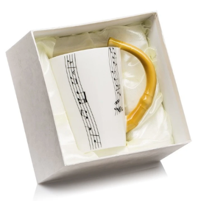 Caneca branca com alça amarela em forma de bengala com pauta musical