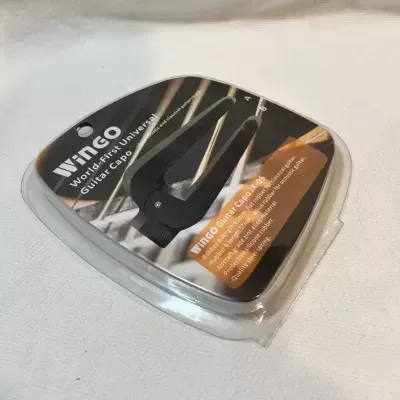 Afinador de guitarra universal Vingo na embalagem preta e transparente sobre superfície branca