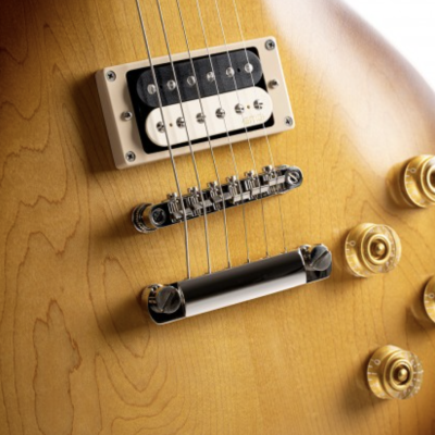 Parte da guitarra elétrica em madeira clara com captador humbucker, ponte metálica e botões dourados