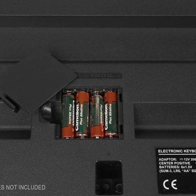 Compartimento de baterias de teclado eletrónico com pilhas AA visíveis