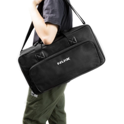 Bolsa preta NUX com alça longa e pegas curtas, sendo transportada ao ombro por uma pessoa