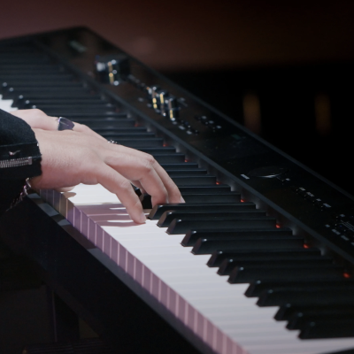 Teclado digital preto com teclas brancas e pretas sendo tocado