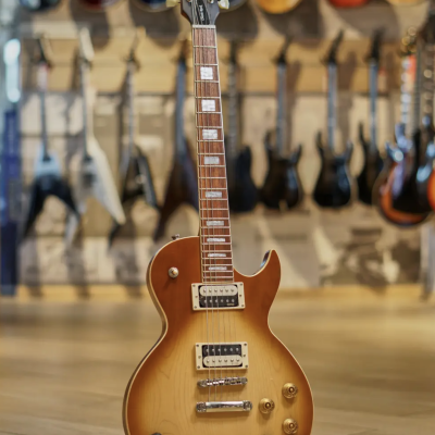 Guitarra elétrica Cort em tom dourado com suporte em chão de madeira