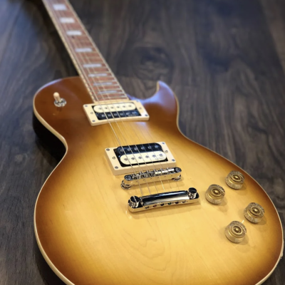 Guitarra elétrica tipo Les Paul sunburst sobre chão de madeira escura