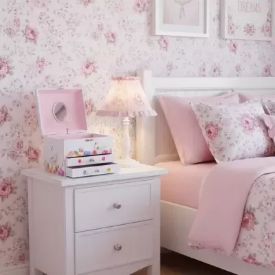 Quarto com papel de parede floral rosa, cama branca com roupa rosa e mesa de cabeceira com candeeiro e caixa de joias floral