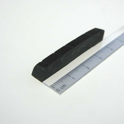 Régua metálica ao lado de objeto preto segmentado sobre superfície branca