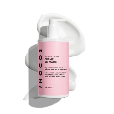 Frasco de creme de mãos rosa com texto em português e tampa branca sobre creme branco espalhado