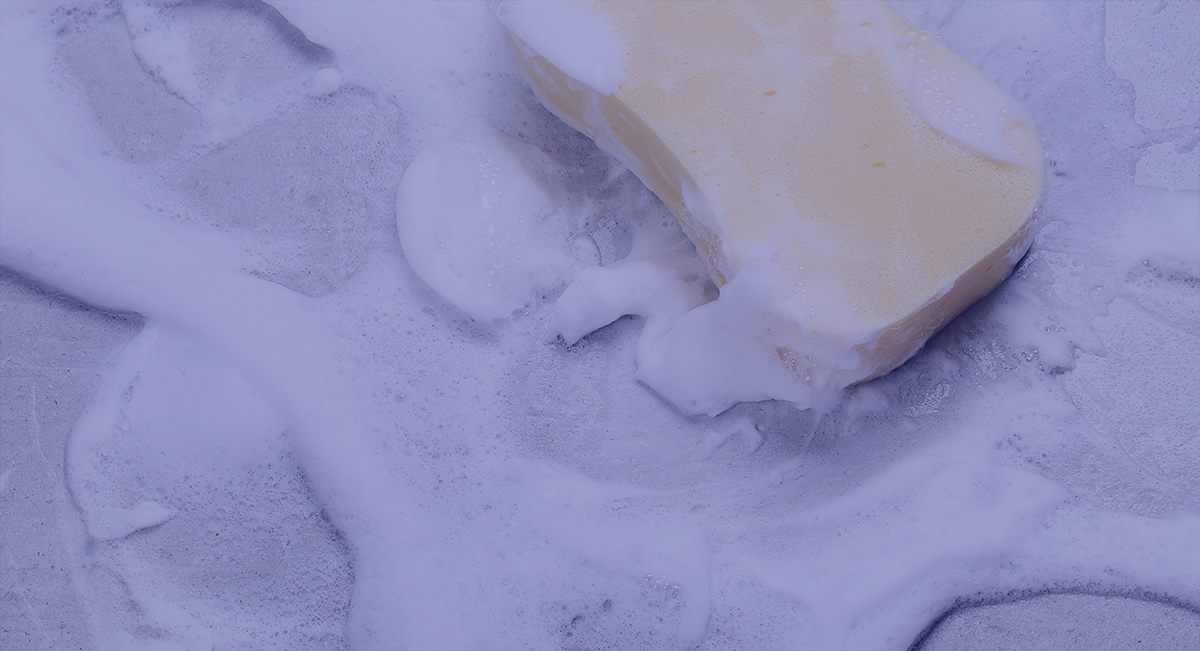 Barra de sabonete amarelo clara com espuma branca em superfície plana