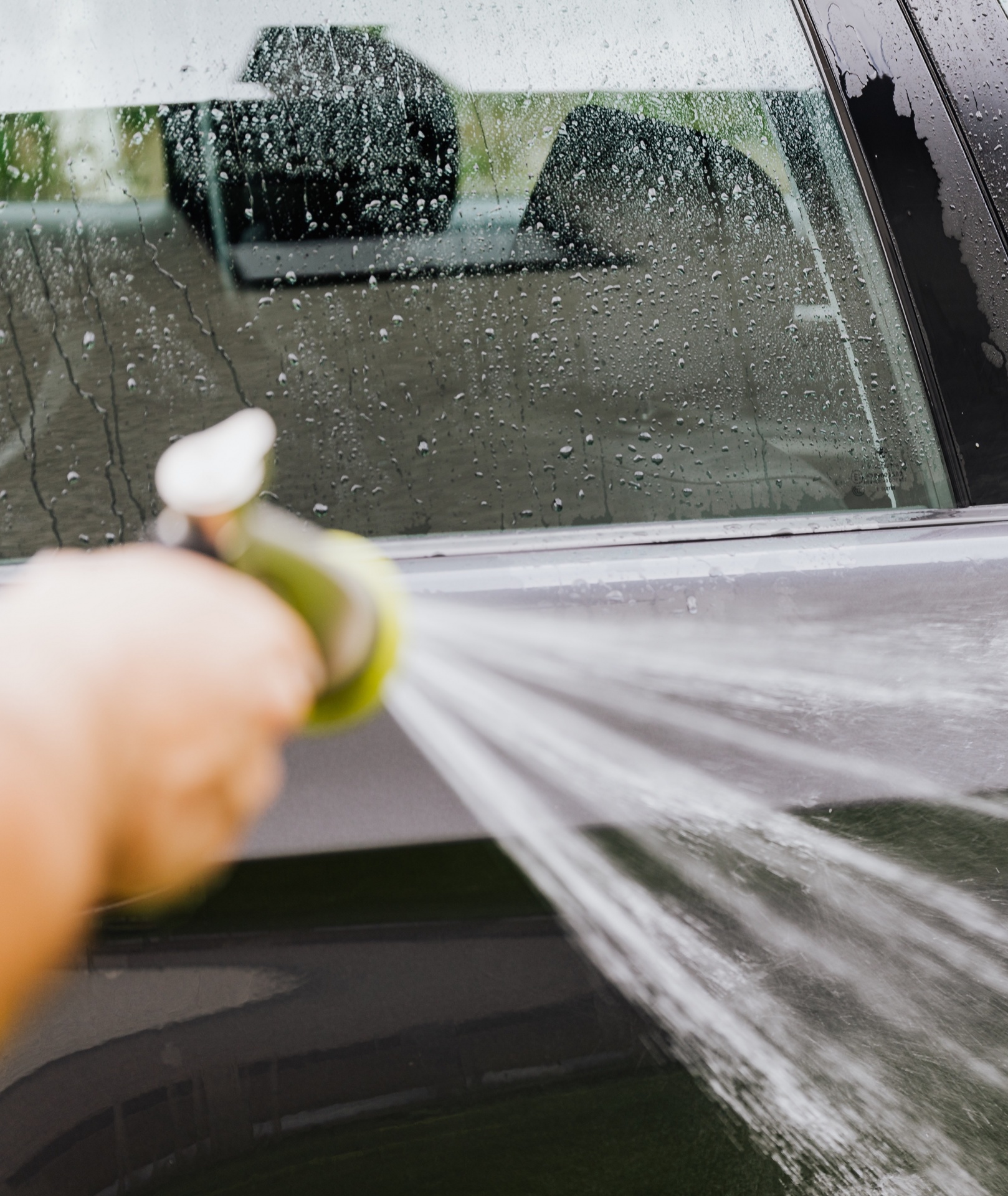 Mangueira de jardim verde a lavar carro preto molhado