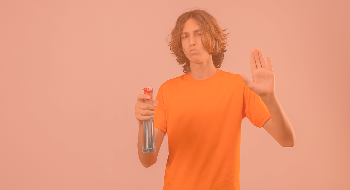 Jovem com t-shirt laranja segura tripé pequeno preto e vermelho e faz sinal de paragem com a mão.