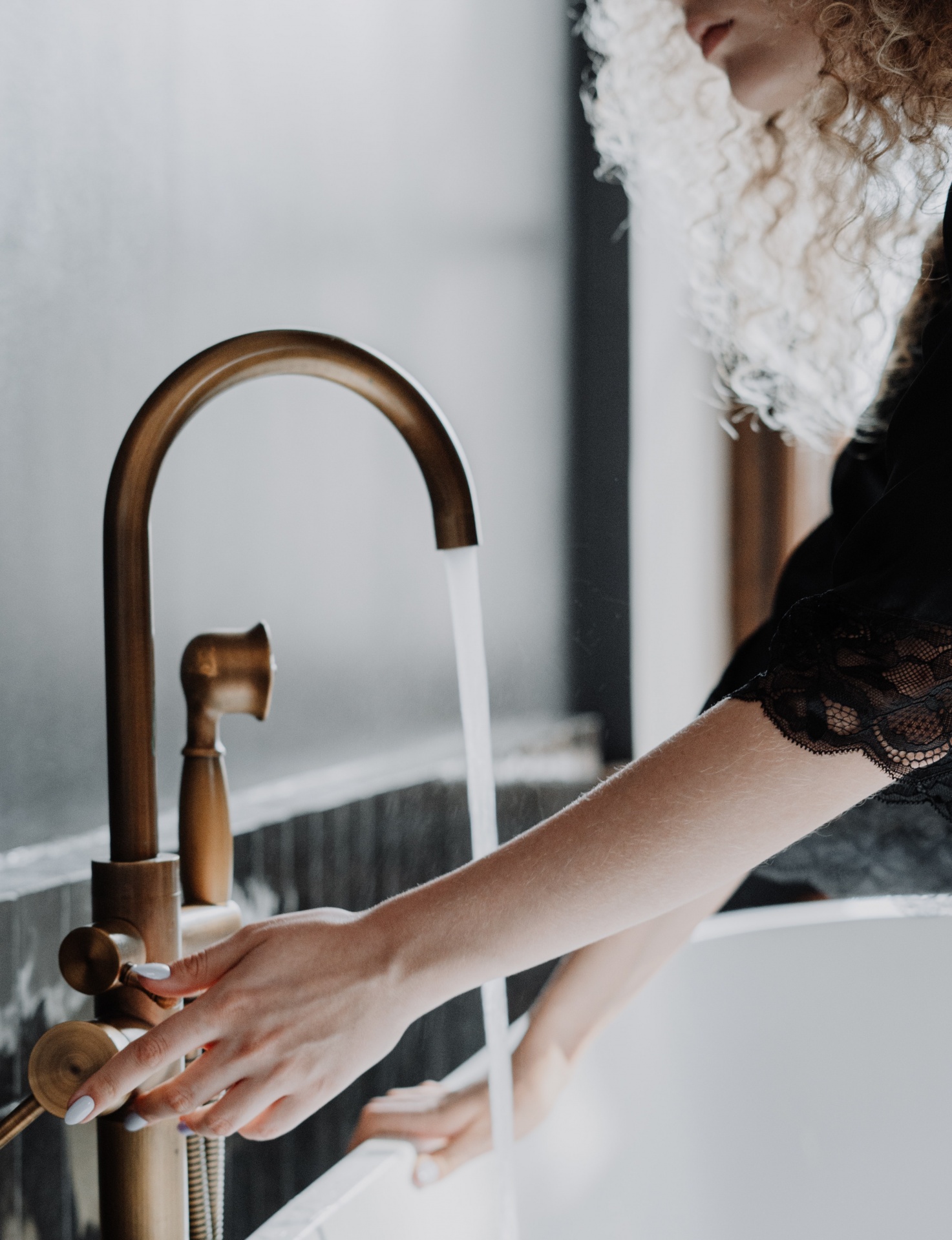 Torneira de banho bronze com pessoa a usar vestido preto