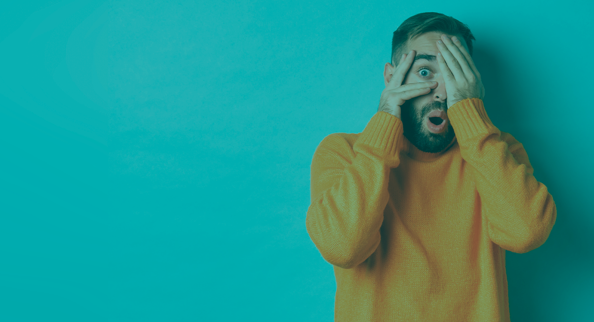 Homem com camisola laranja, parede azul, expressão de surpresa