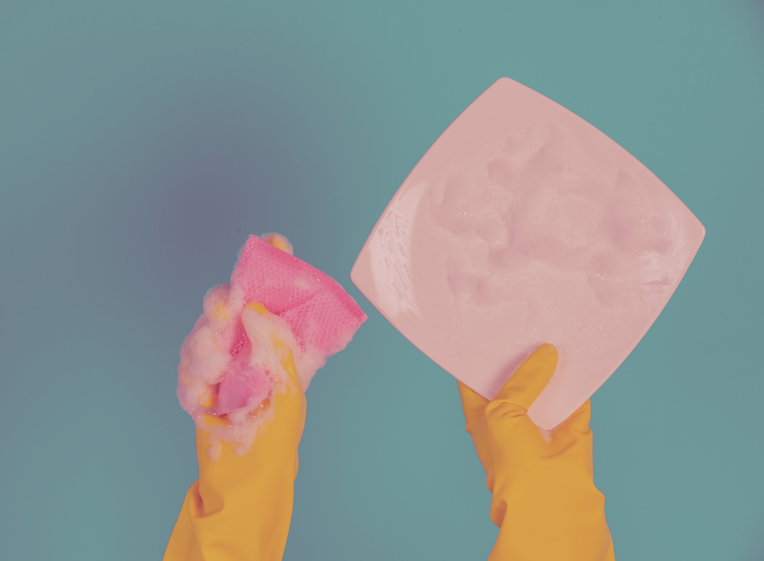 Mãos com luvas amarelas seguram esponja com espuma e prato branco