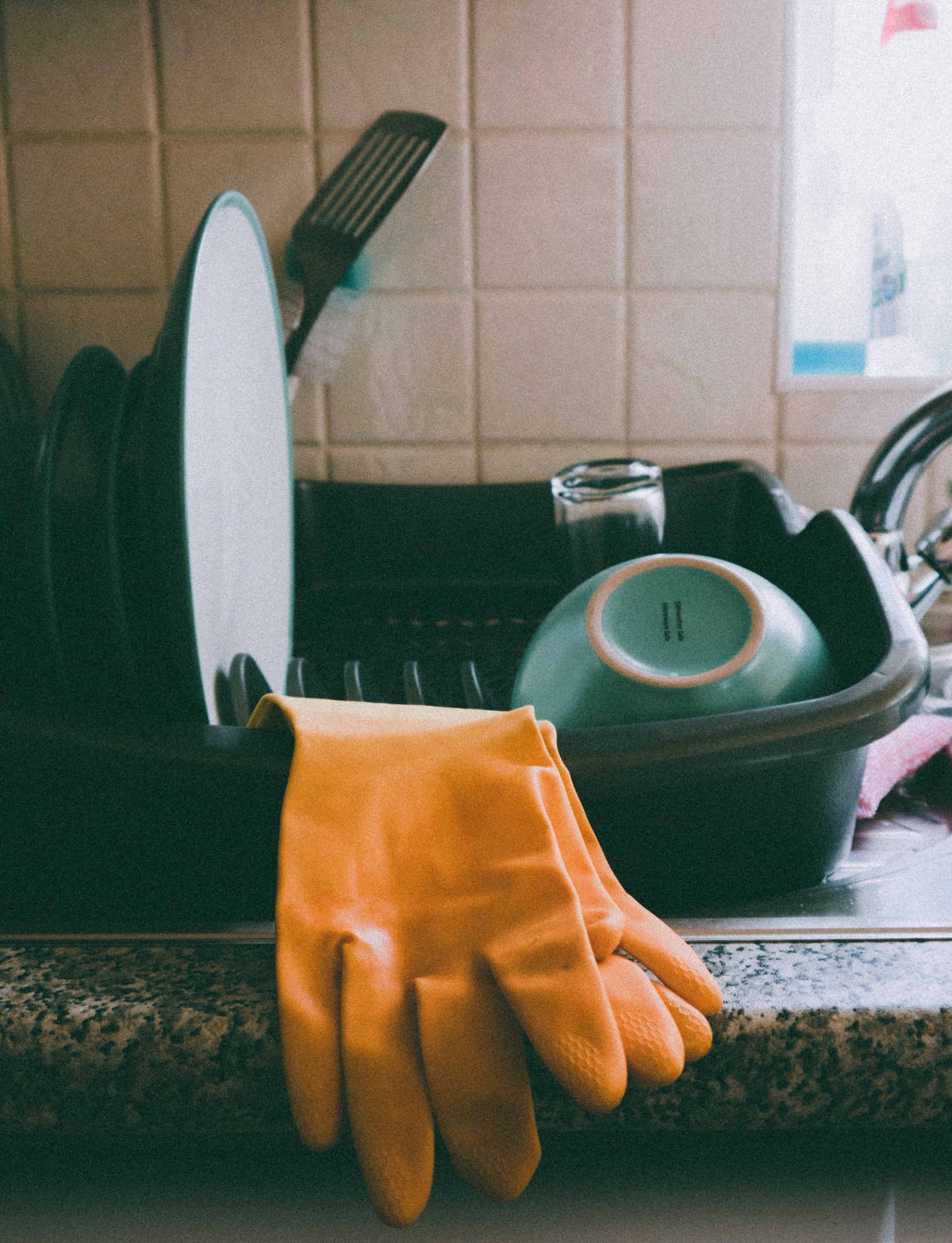 Escorredor de louça com pratos, tigela, copo e luva de borracha.