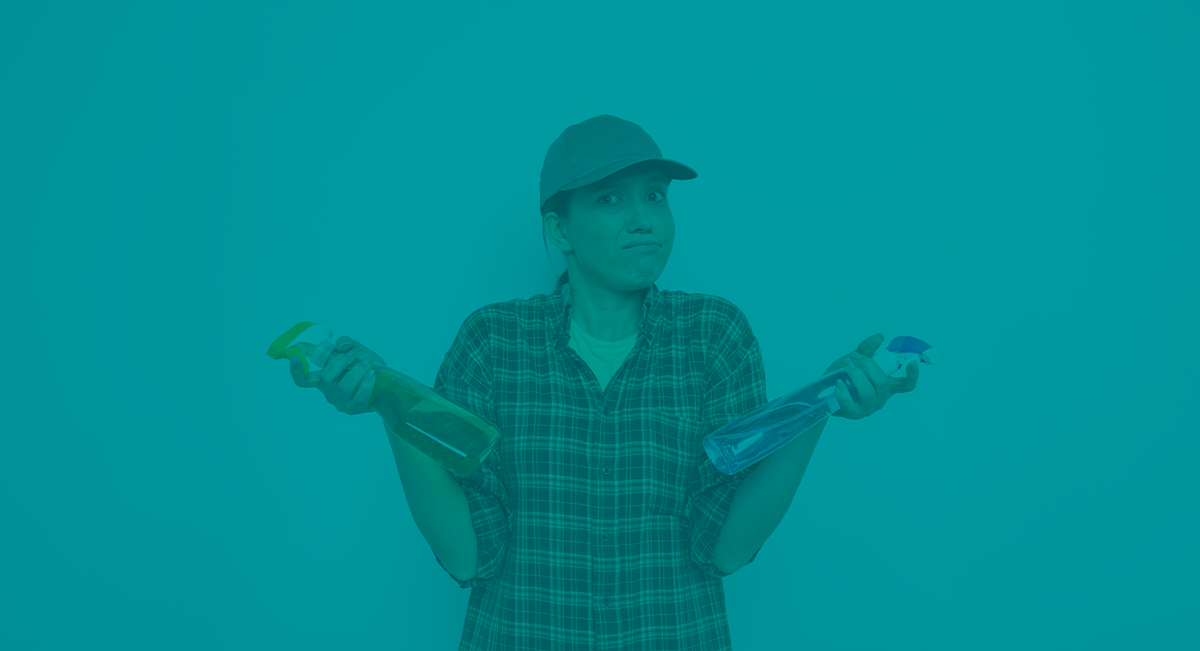 Pessoa segurando dois frascos de spray, um verde e um azul, vestindo camisa xadrez e boné.