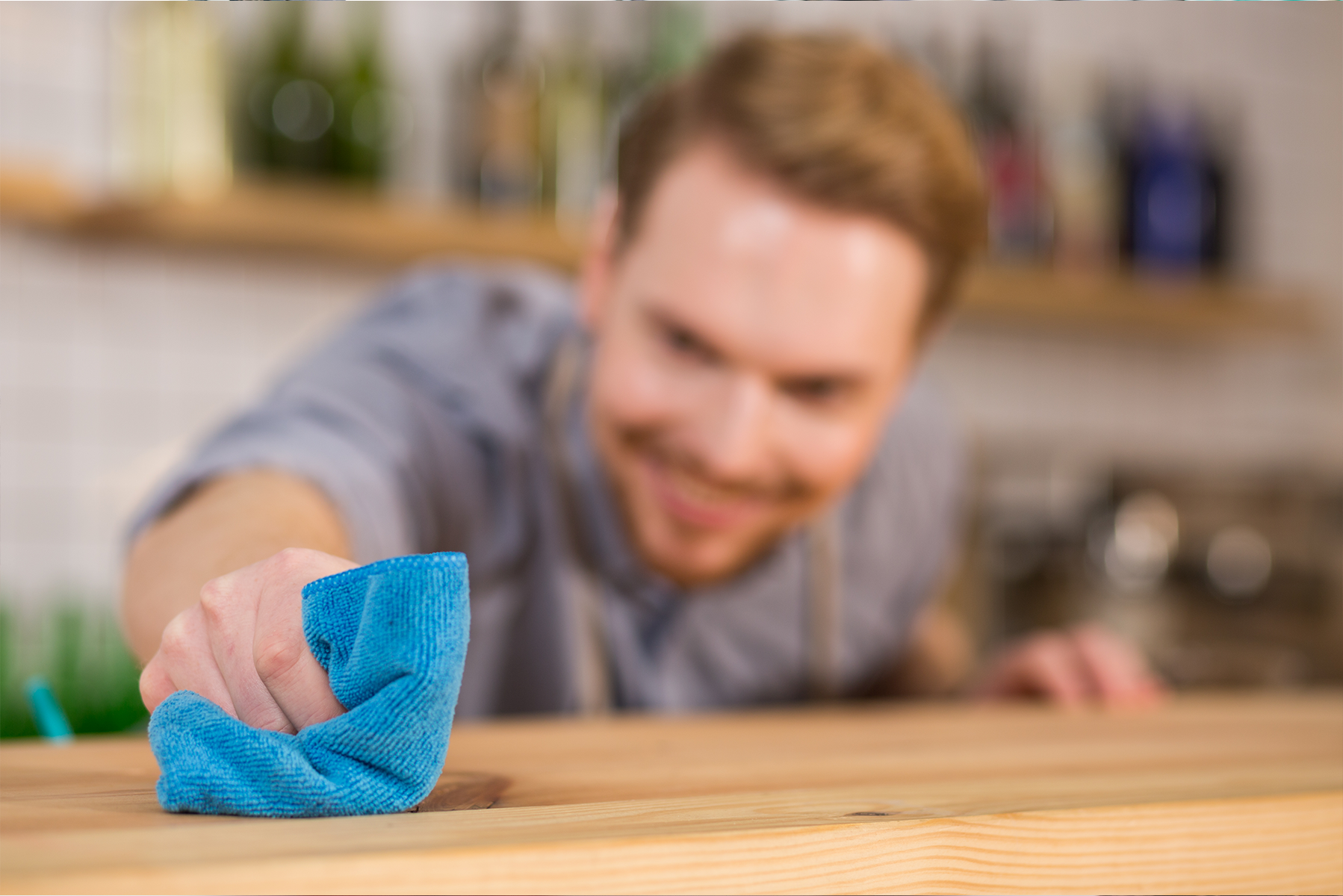 Detergente neutro multiusos - BIOCLEAN MARE Homem a limpar balcão de madeira com pano azul