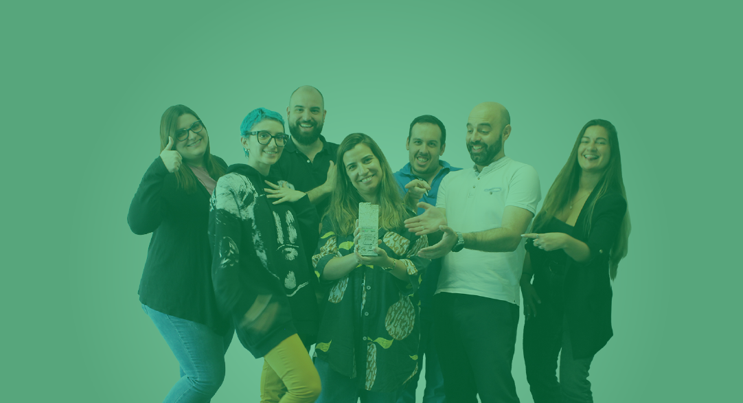 Sete pessoas a sorrir num fundo verde claro, mostrando um telemóvel