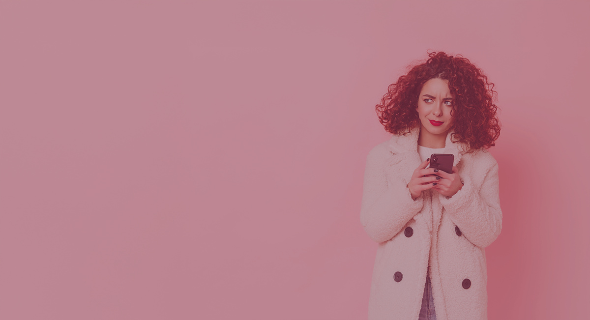 Mulher com casaco branco usando smartphone em fundo rosa