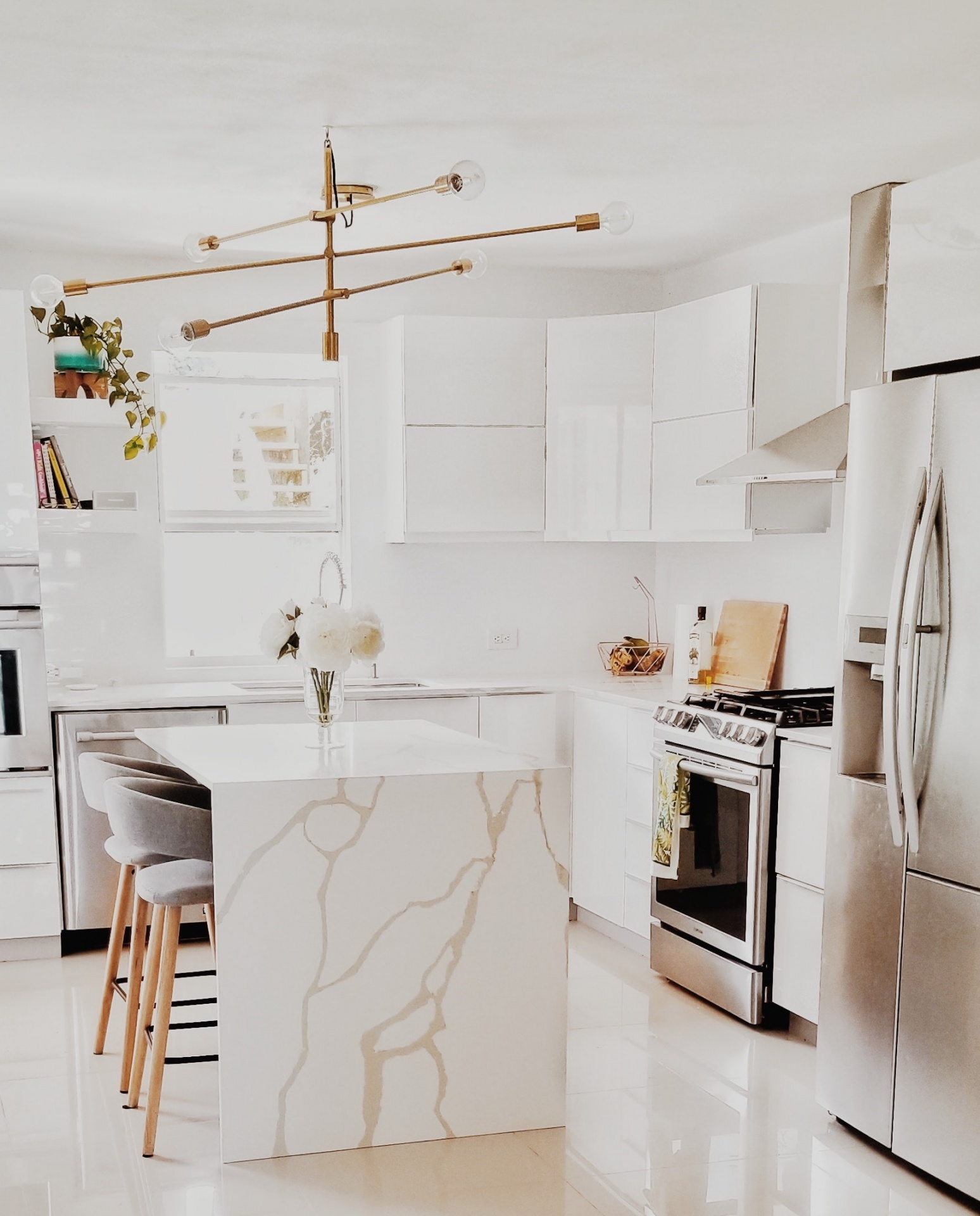 Cozinha branca moderna com ilha em mármore e eletrodomésticos inox