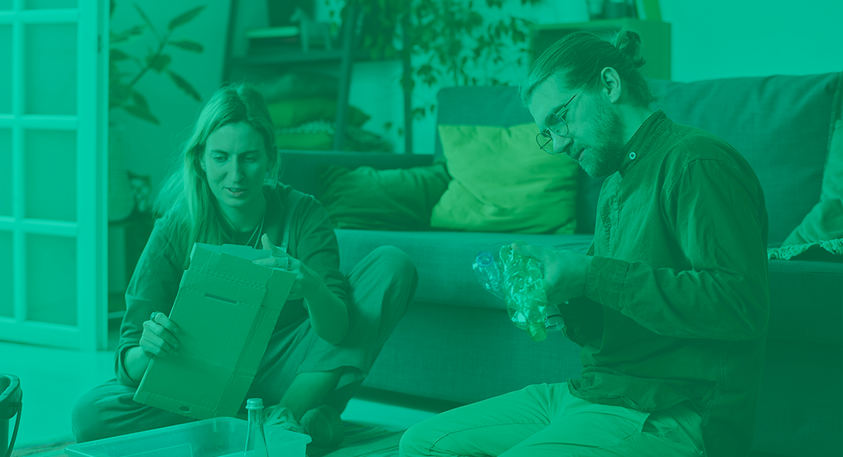 Duas pessoas desembrulhando embalagem numa sala com sofá verde.