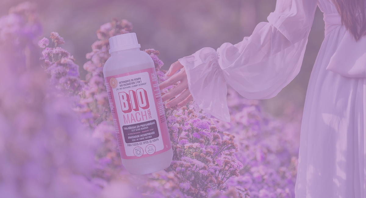 Frasco branco com rótulo B10 MACH segurado em campo de flores lilases