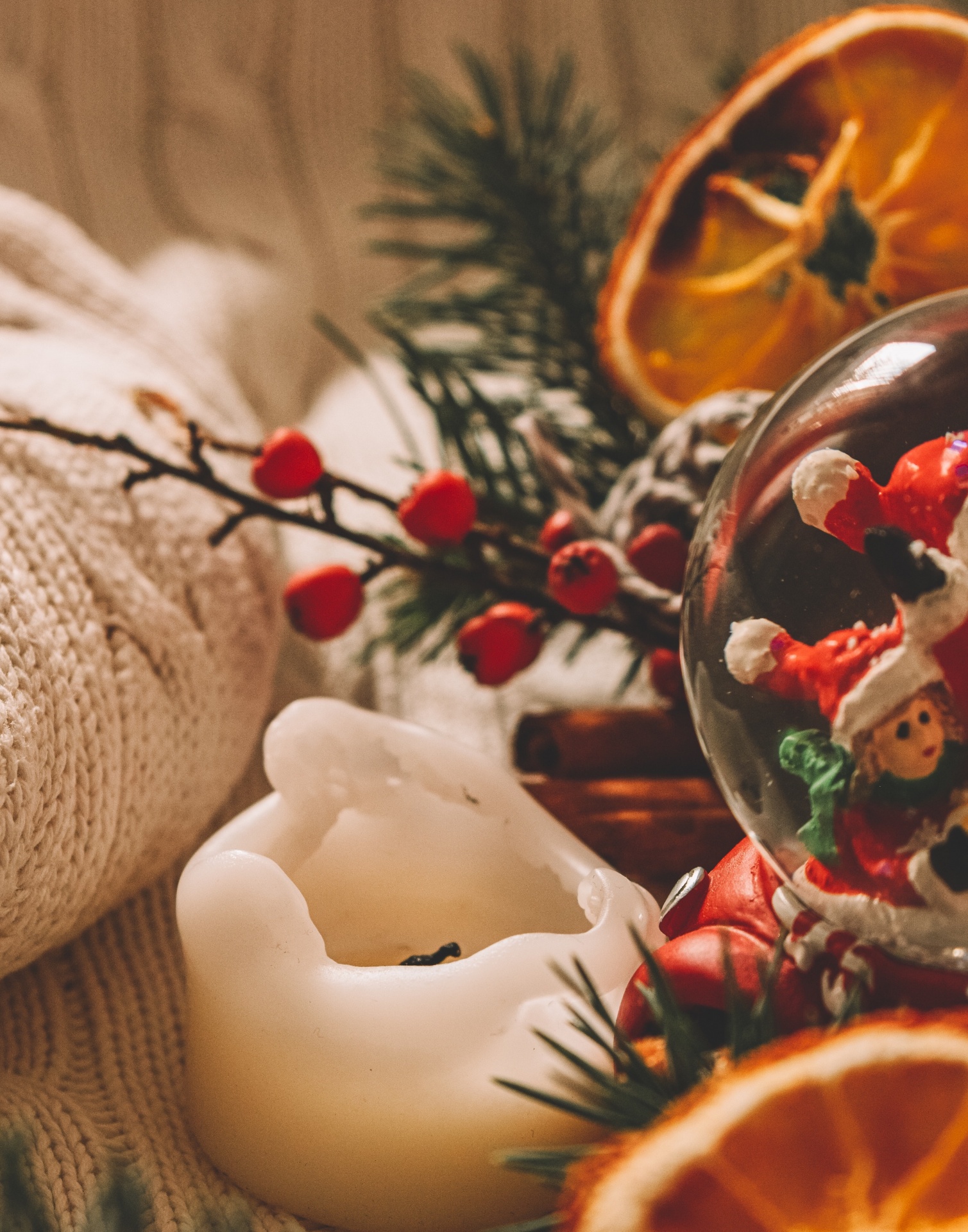 5 medidas práticas para um Natal em segurança Castiçal de vela branca e enfeites de Natal num fundo de malha bege