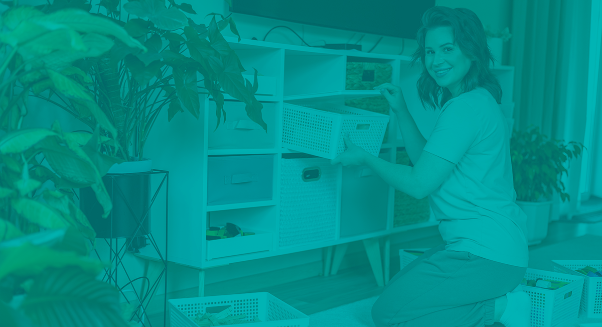 Móvel branco com nichos e cestos de vime, mulher a organizar cesto, plantas ao redor