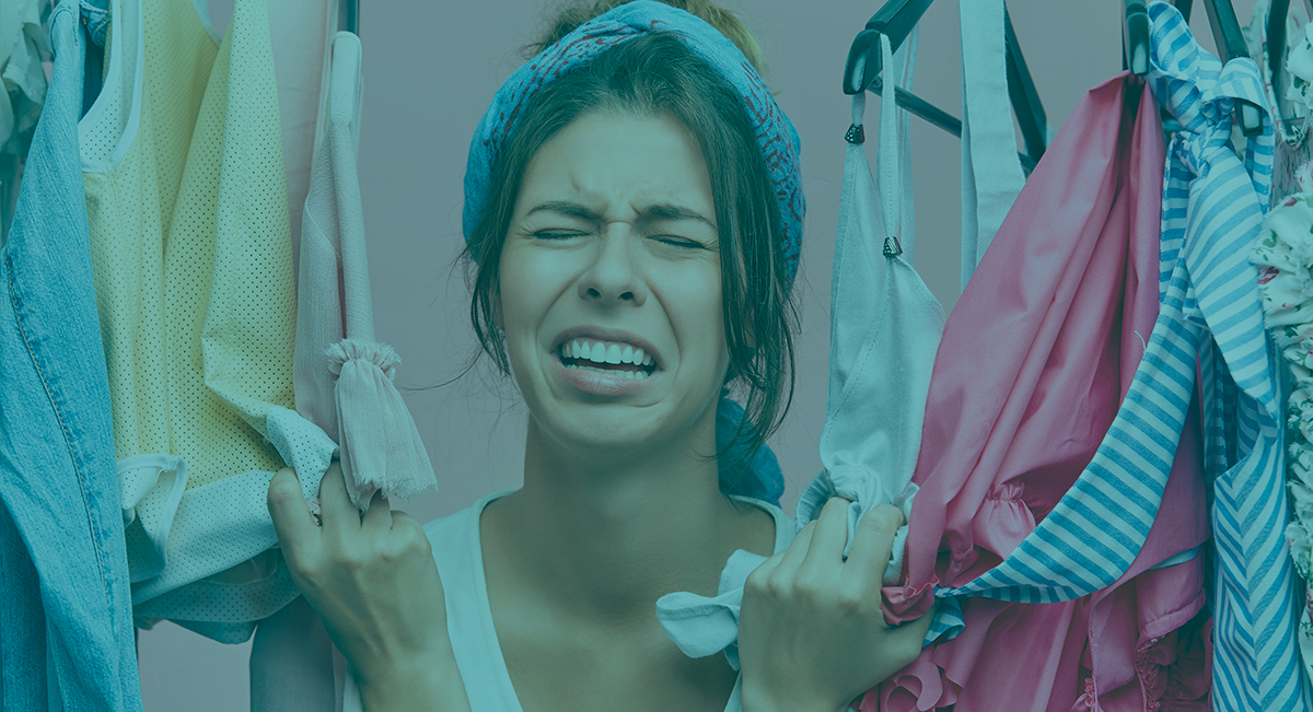 Mulher a segurar várias roupas penduradas em cabides, incluindo camisola amarela e roupa interior branca