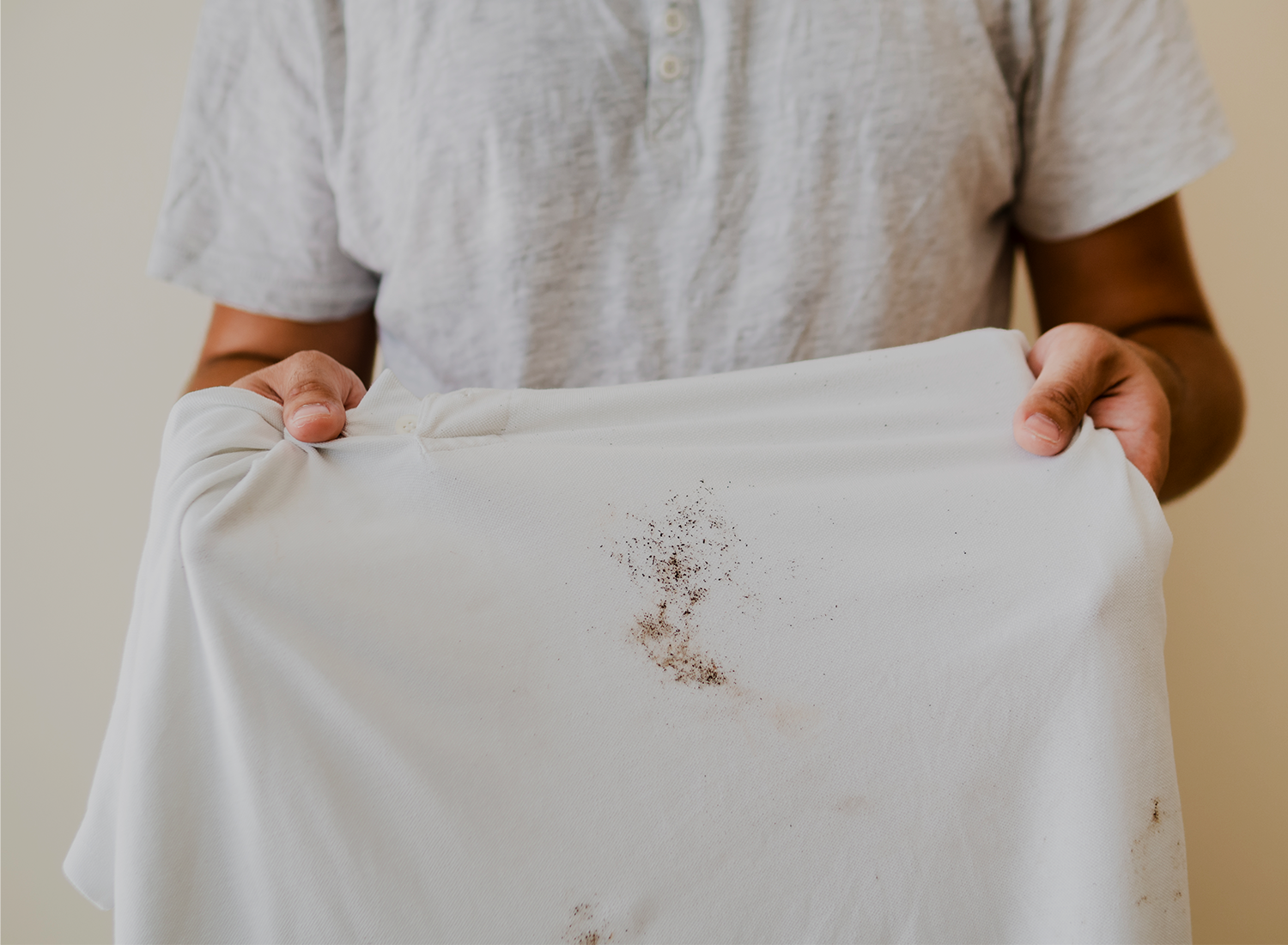 Pessoa a segurar uma t-shirt branca com manchas de sujidade