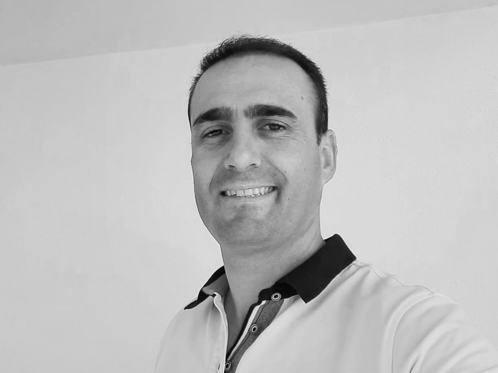 Escolher um desinfetante de mãos eficaz Homem a sorrir com t-shirt polo branca de gola preta em fundo branco