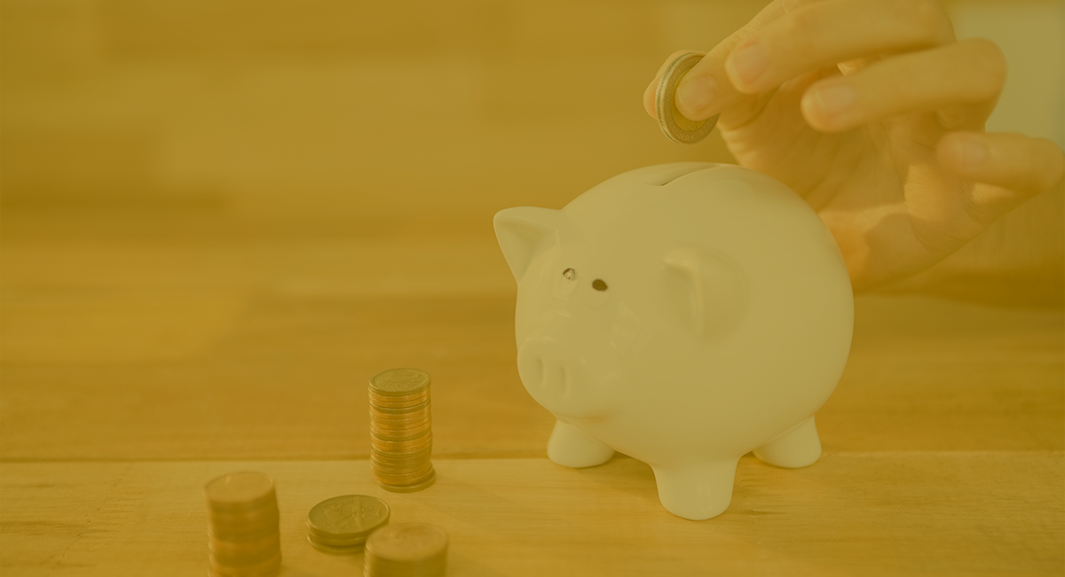 Mealheiro em forma de porco branco com moedas e mãos a colocar uma moeda