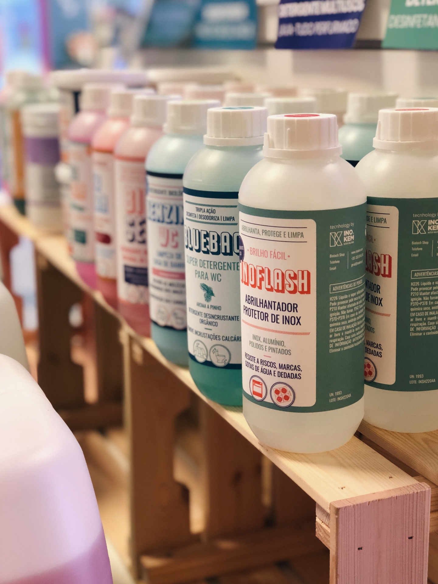 Garrafas de produtos de limpeza agrupadas numa prateleira de madeira