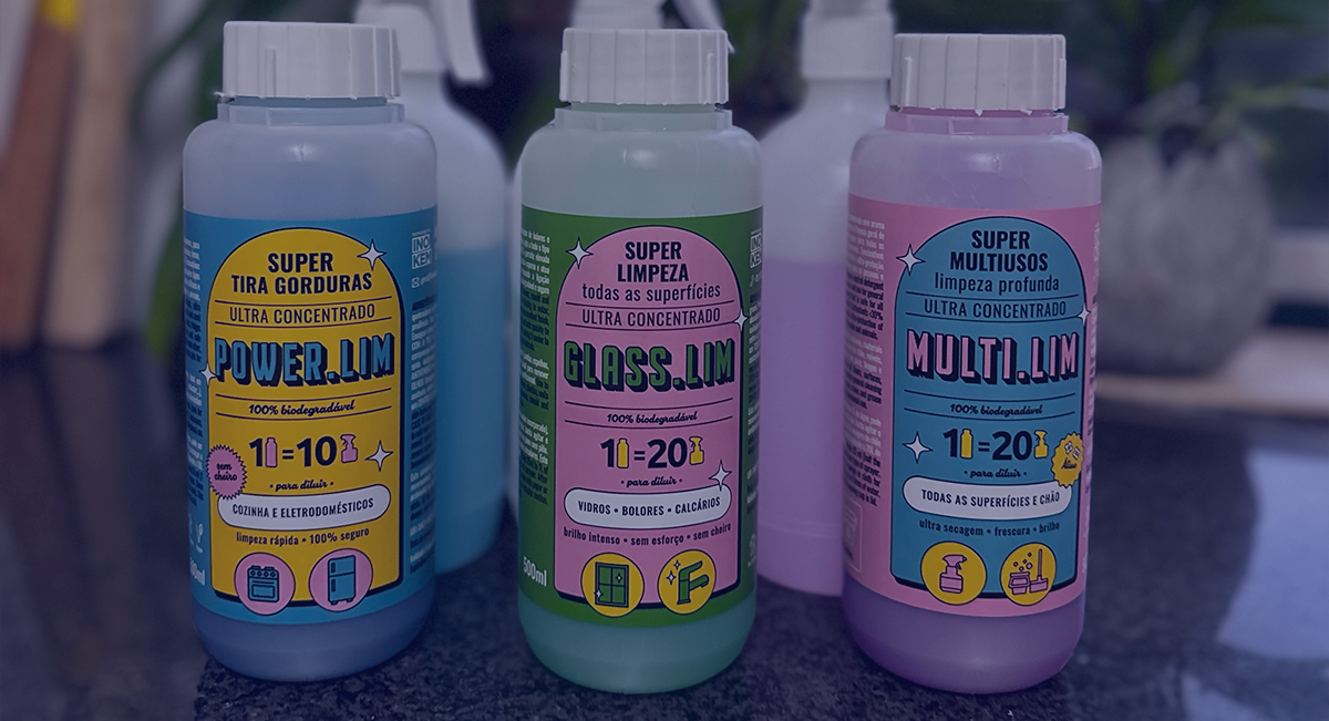 Três frascos coloridos de produtos de limpeza Super com etiquetas coloridas e tampas brancas numa superfície cinza