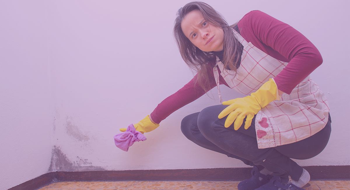 Mulher a limpar parede com humidade usando pano e luvas amarelas