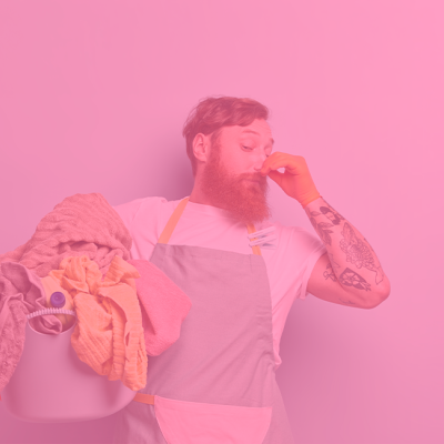Homem com avental segurando balde com roupa em fundo rosa