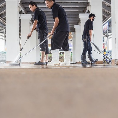 Três homens a limpar piso industrial com mop e calçado impermeável