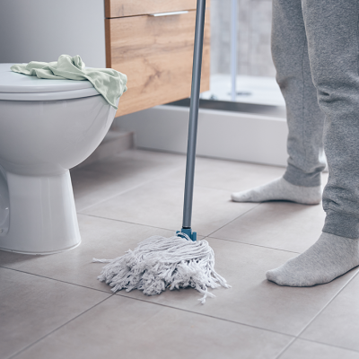 Pessoa a limpar chão de WC com esfregão branco e azul